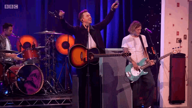 a band performing on stage with bbc written on the bottom