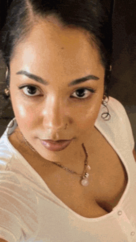 a woman wearing a white shirt and a necklace with a pearl on it