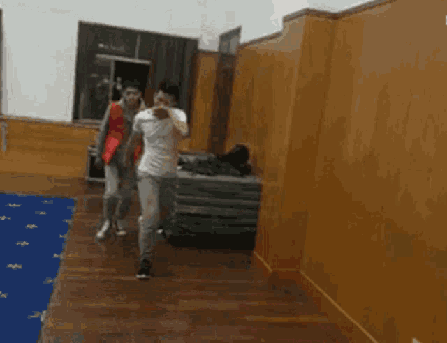 a couple of people walking down a hallway with a blue rug