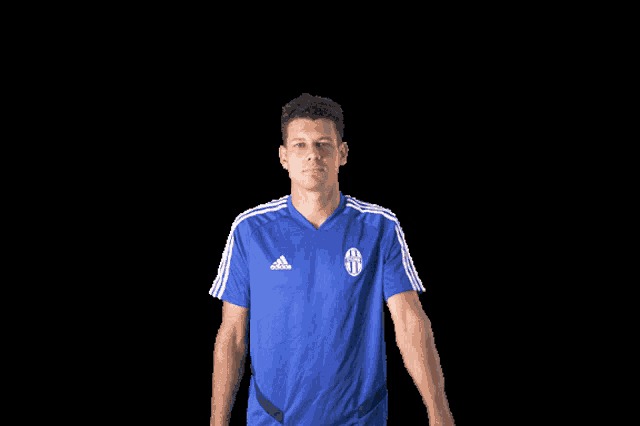 a man wearing a blue adidas shirt is standing in front of a black background