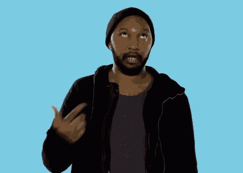 a man with a beard wearing a black hat and a black jacket is pointing at the camera .