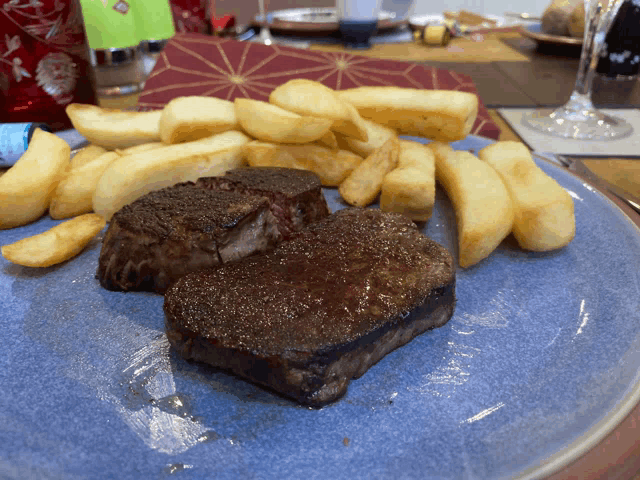 a blue plate topped with steaks and french fries