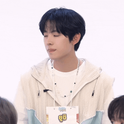 a young man wearing a white sweater and a white t-shirt that says ' a ' on it