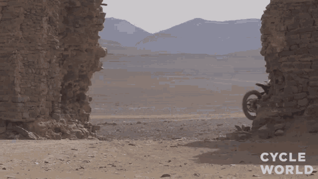 a person riding a motorcycle in the desert with the words cycle world written on the bottom