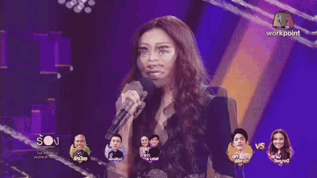 a woman singing into a microphone in front of a screen that says workpoint