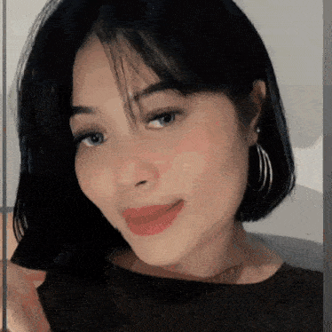 a woman with short black hair and hoop earrings is smiling