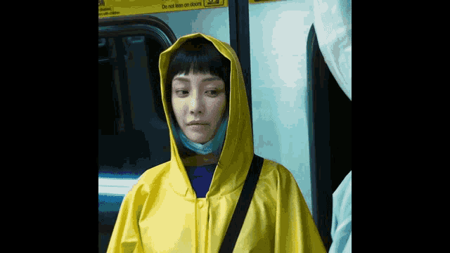 a woman wearing a yellow raincoat has a sign on the door that says " do not lean on doors "