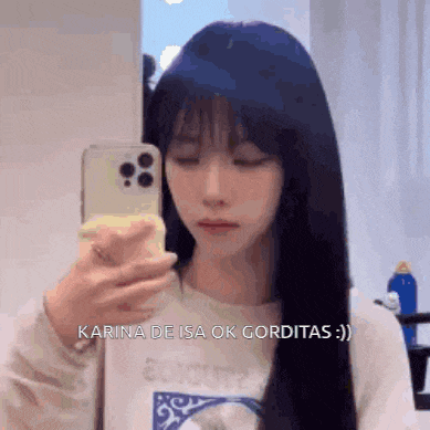 a woman with long blue hair is taking a selfie in a mirror .
