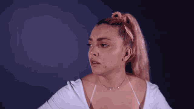 a woman with pink hair is wearing a white top