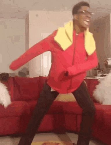 a man in a red jacket and yellow scarf is dancing in a living room .