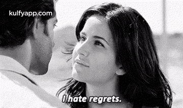 a man and a woman are kissing in a black and white photo . the woman is saying `` i hate regrets '' .