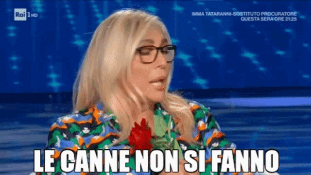 a woman wearing glasses holds a red rose in her hand and says le canne non si fanno