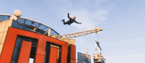a man is falling from the top of a building with a crane behind him