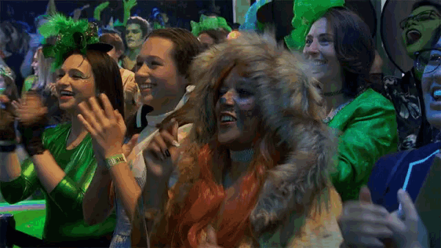 a group of women in green clothes are clapping