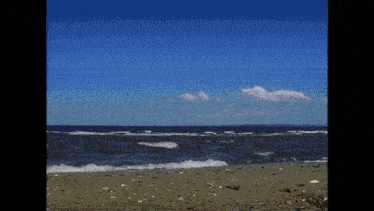 a beach scene with waves crashing on the sand and a blue sky