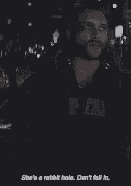 a man with a beard is standing in the dark with a rabbit hole in his chest .