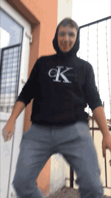 a man wearing a black hoodie with the letter ck on the front