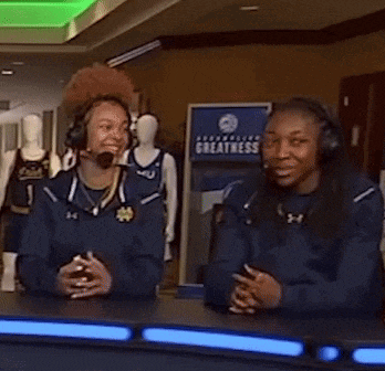 two women wearing headphones are sitting in front of a sign that says " greatness "