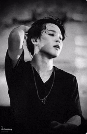 a black and white photo of a man wearing a black shirt and a necklace .