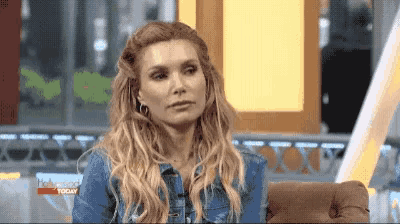 a woman is sitting on a couch wearing a denim jacket .
