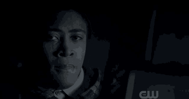 a woman is crying in a dark room while looking at a computer screen .