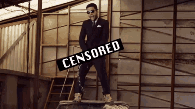 a man in a suit is standing on a tire with a sign that says censored on it