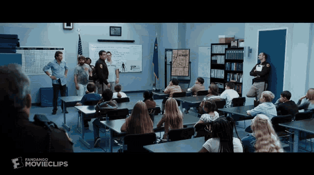 a group of people sitting at desks in a classroom with a sign that says movieclips
