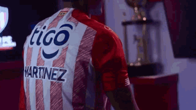 a man wearing a red and white striped jersey with the name martinez on it