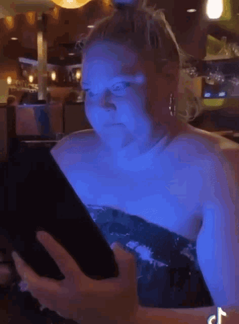 a woman in a blue dress is looking at a cellphone
