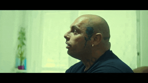 a man with a tattoo of a rose on his forehead has a black shirt on