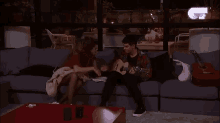 a man is playing an acoustic guitar while a woman watches
