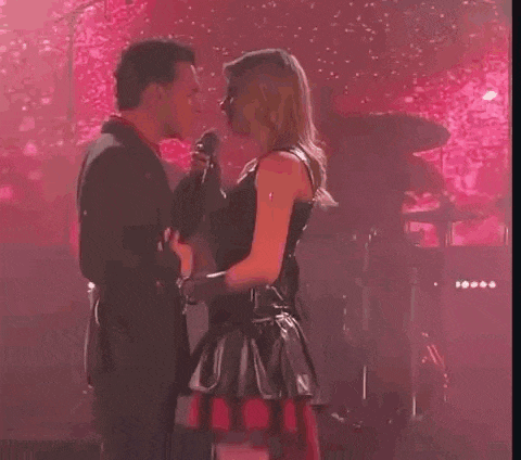 a man and a woman are dancing on a stage in front of a drum set .