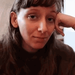a woman is resting her head on her hand and looking at the camera .