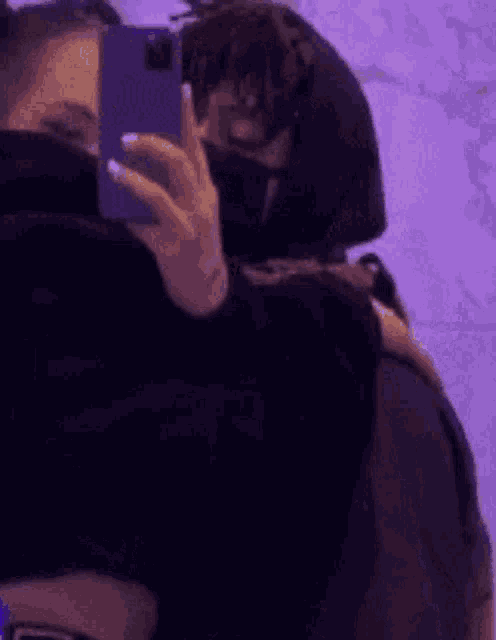 a man is taking a picture of himself in a mirror while hugging another man .