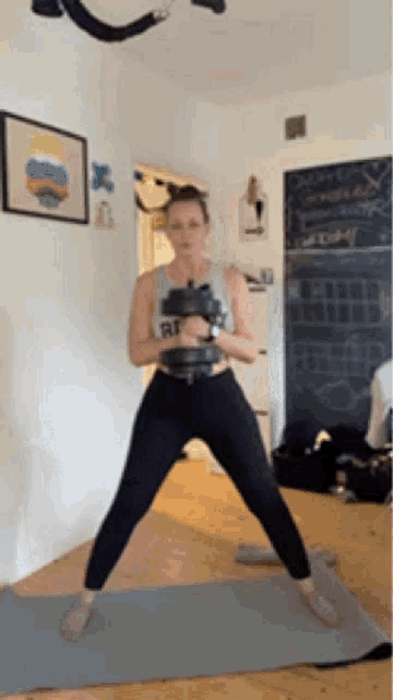 a woman is standing on a yoga mat with a dumbbell in her hand .