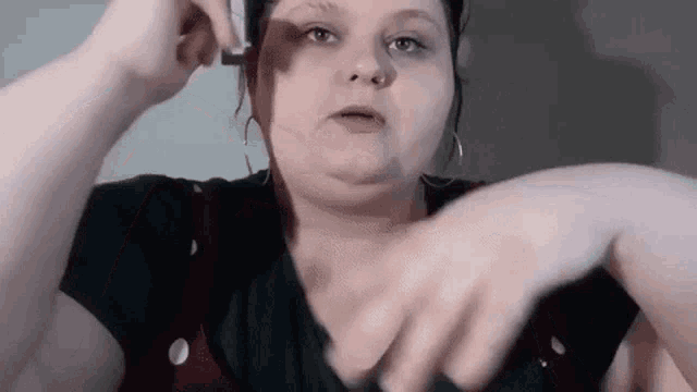 a woman is holding a small object in her hand and making a face .