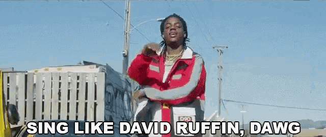 a man in a red jacket is singing like david ruffin dawg