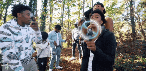 a group of young men are standing in the woods and one of them is wearing a sweatshirt with cars on it
