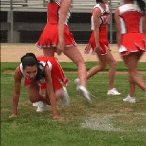 a group of cheerleaders in red uniforms are crawling on the field