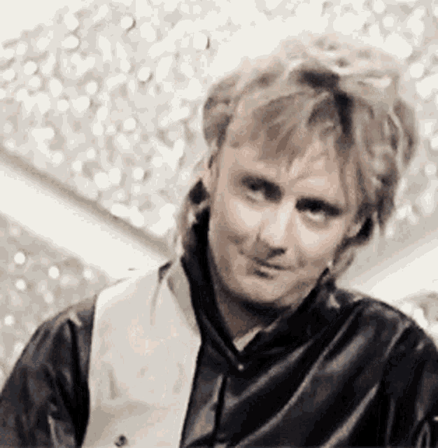a man wearing a black leather jacket and a white vest