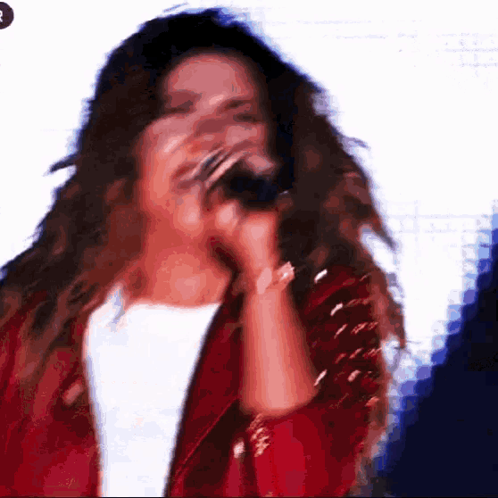 a blurry picture of a woman singing into a microphone with the letter o on the bottom right