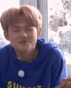 a young man wearing a blue hoodie with the word sunset on it is making a funny face .