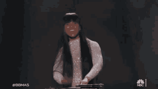 a woman is standing in front of a keyboard on a stage and laughing .