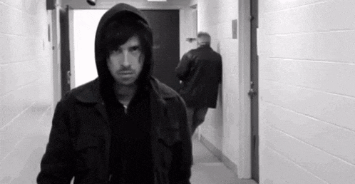 a black and white photo of a man in a hooded jacket