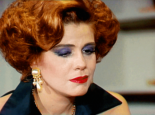 a close up of a woman 's face with red hair and purple eye shadow