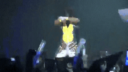 a man in a yellow vest is standing in front of a crowd on a stage