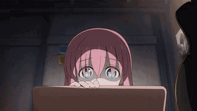 a girl with pink hair is looking at a laptop