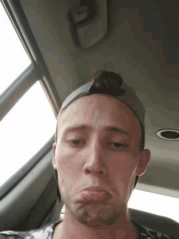 a man wearing a hat is sitting in a car looking out the window