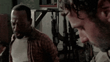 a man in a plaid shirt is talking to another man