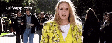 a woman in a plaid jacket is standing in front of a crowd of people .